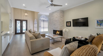 A cozy living room in a home in Tierra Santa at McCormick Ranch, featuring a fireplace and wicker furniture.