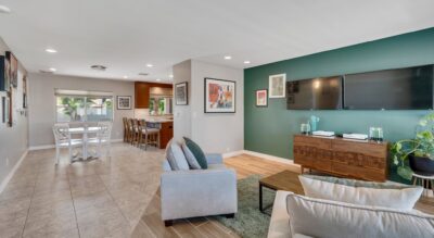 Modern living room in Scottsdale at 6309 E Friess Dr, with an open floor plan, featuring a seating area, wall-mounted TV, and adjacent dining space.